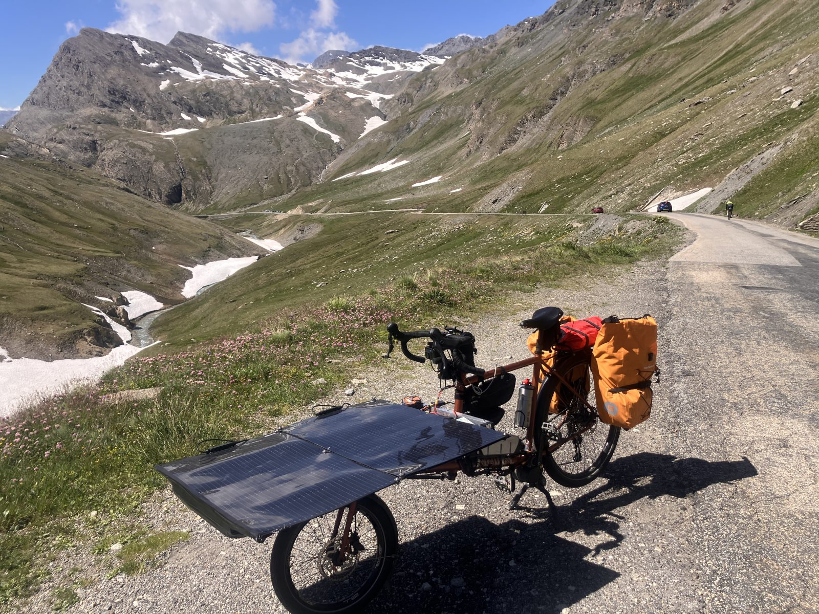 Solar-Lastenrad mit Modul auf der Frontbox, geparkt an einer Alpenpassstraße während des Sun Trip 2026