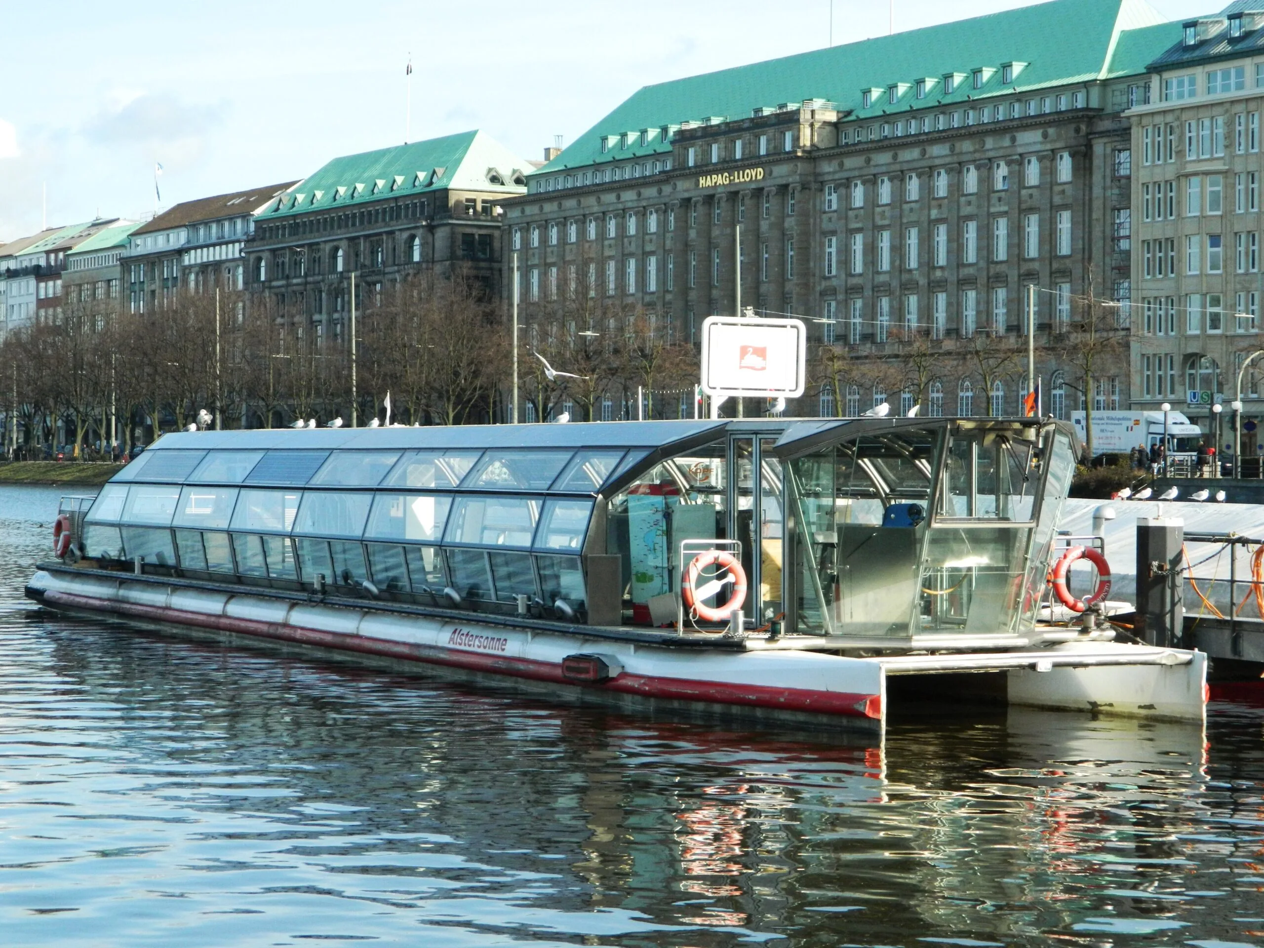 The glass-roofed stainless-steel solar boat Alstersonne at its pier on the Binnenalster in Hamburg
