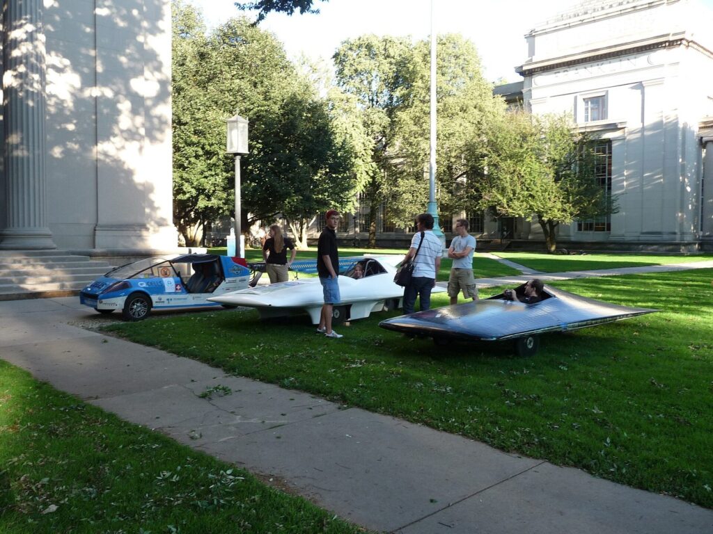 The Solartaxi visiting the MIT solar car team, next to its race cars.