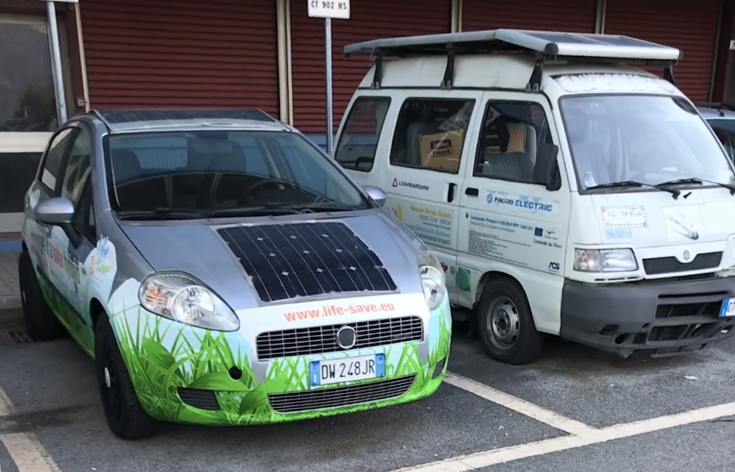 A Fiat Punto with flexible solar panels on its bonnet and roof next to a Piaggio Porter electric van at the University of Salerno