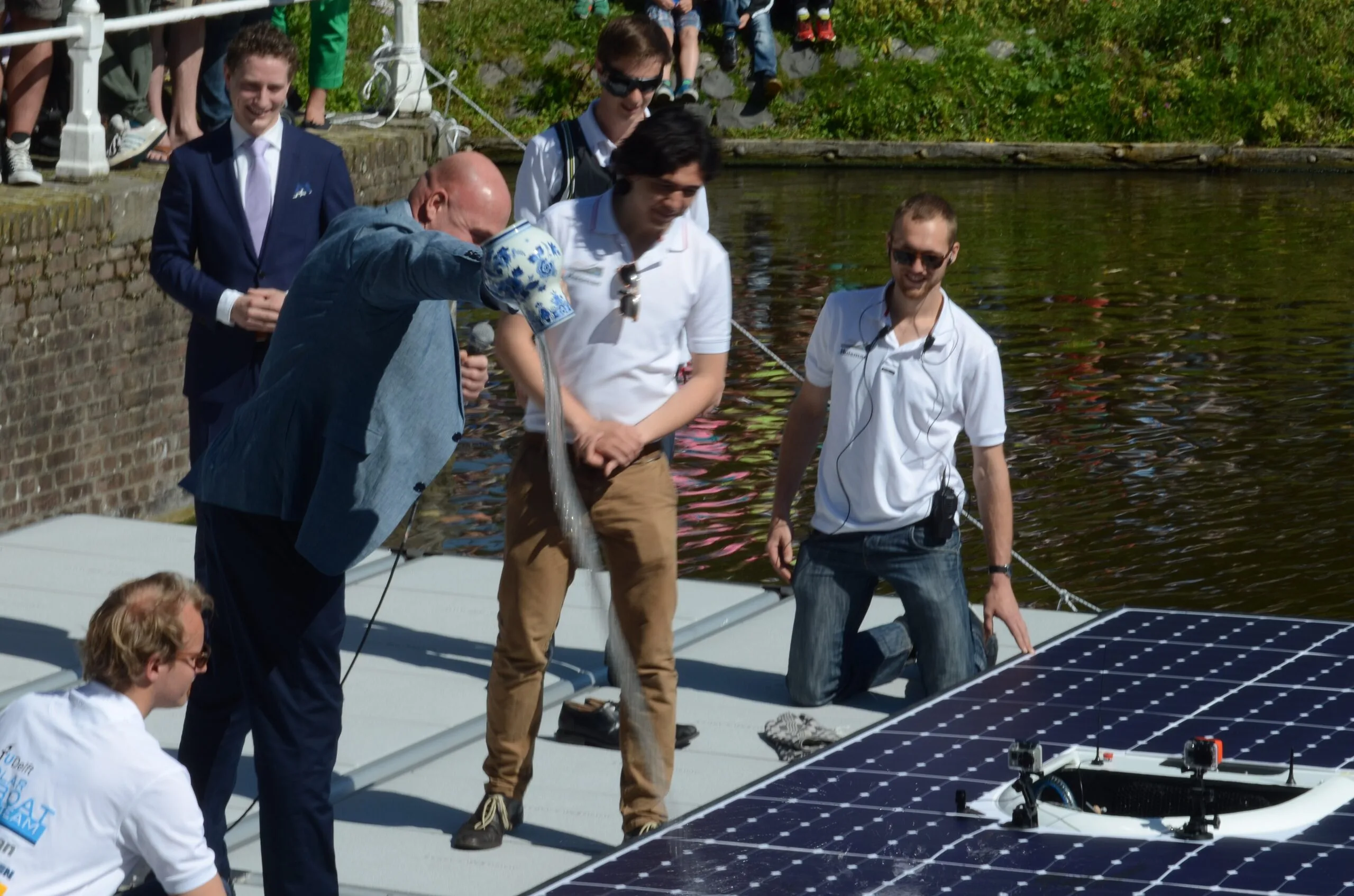 Astronaut André Kuipers christening the TU Delft solar boat, its solar panel deck in the foreground