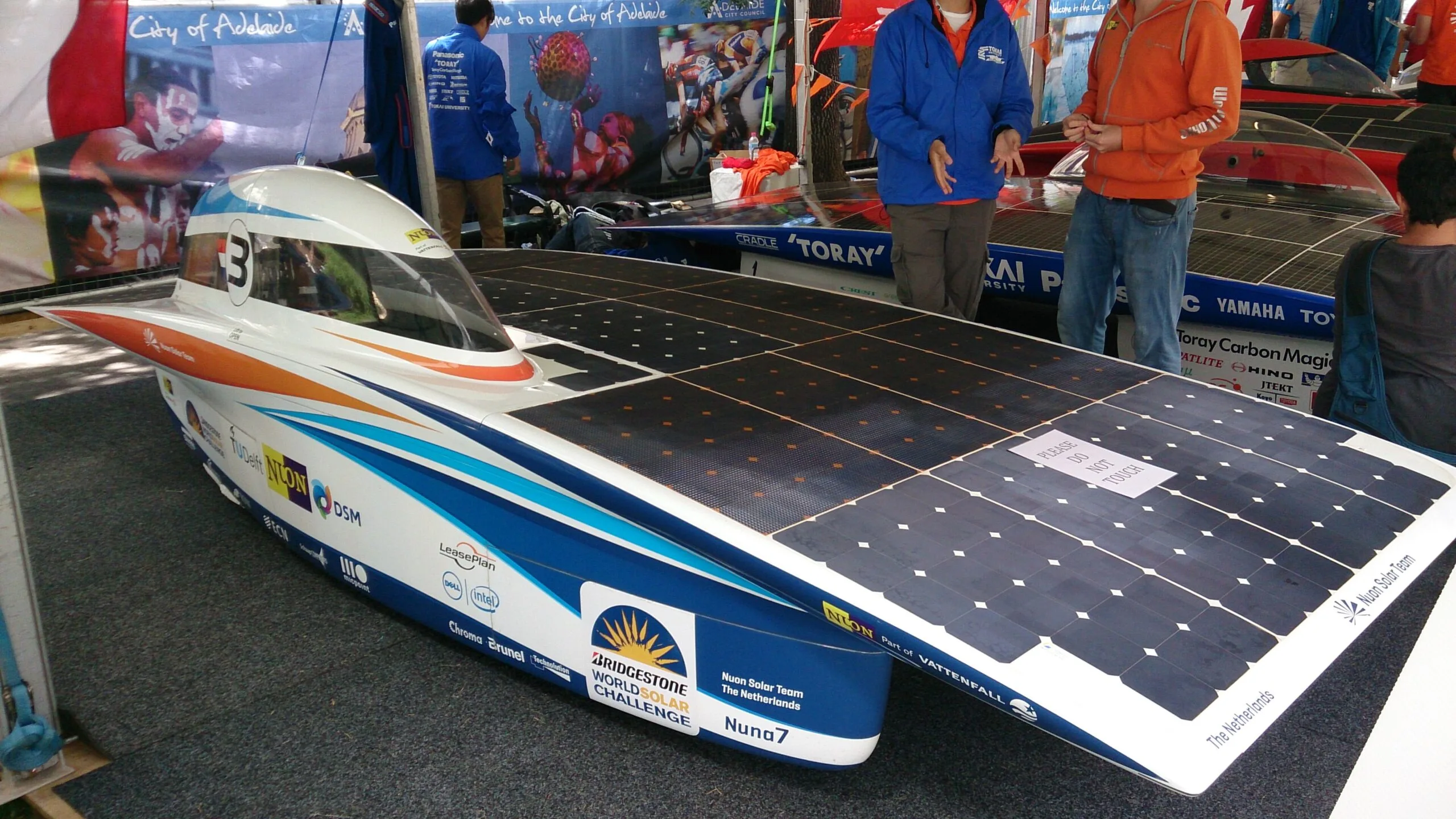 The flat, asymmetric Nuna 7 solar race car with its blue and orange livery on display