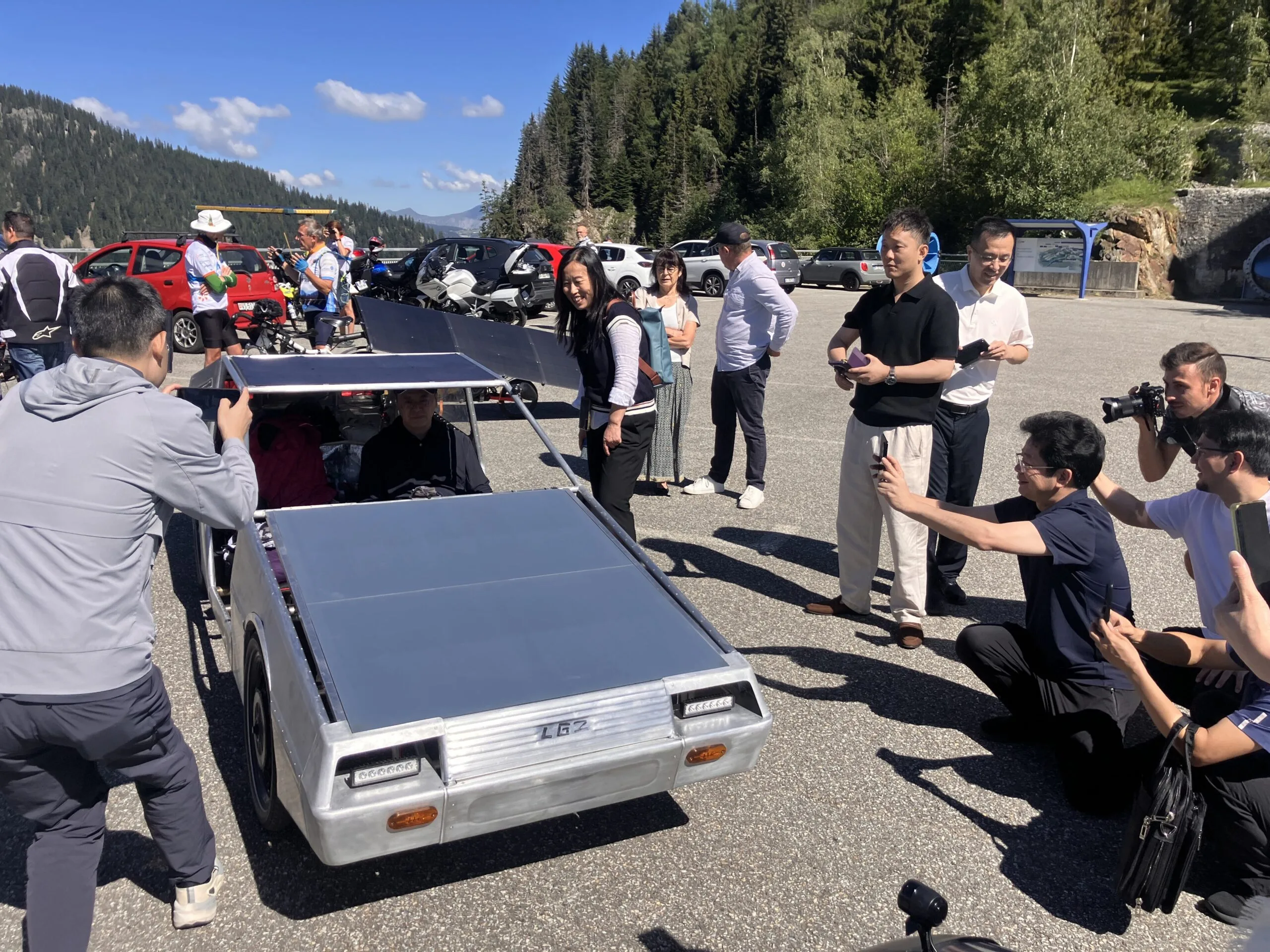 The VéLorean, a low silver solar quadricycle with a flat solar roof, surrounded by people at the 2026 Sun Trip