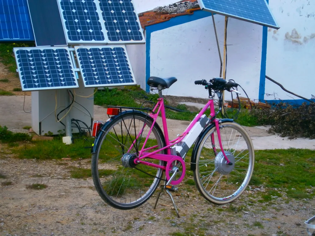 Pink e-bike charging from a small two-panel solar station