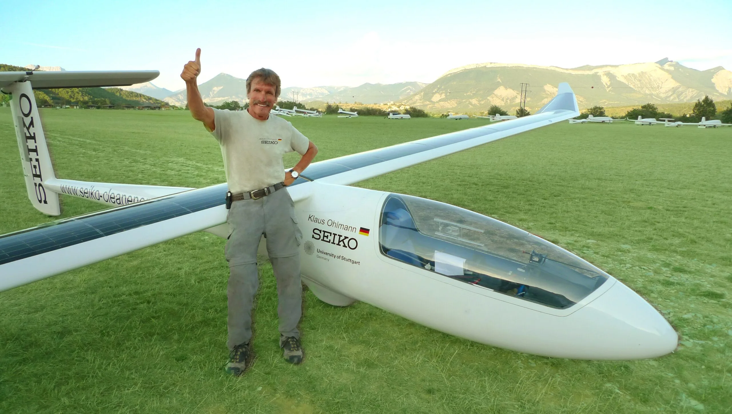 Pilot Klaus Ohlmann giving a thumbs up next to the long white icaré 2 solar glider on an airfield