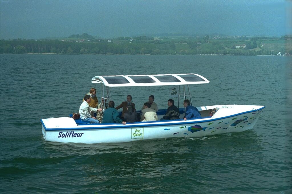 The small open solar boat Solifleur with passengers under its solar roof on a Swiss lake